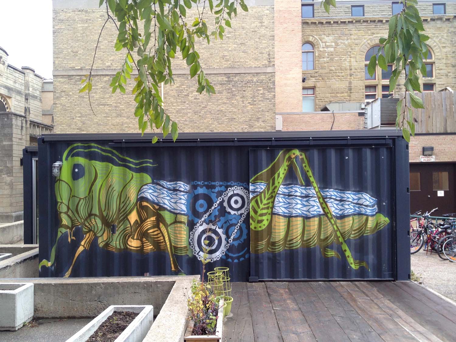 Image of the side of the UWSA BikeLAB, with a mural of a cricket. The midsection of the cricket's body is composed of bicycle gears.