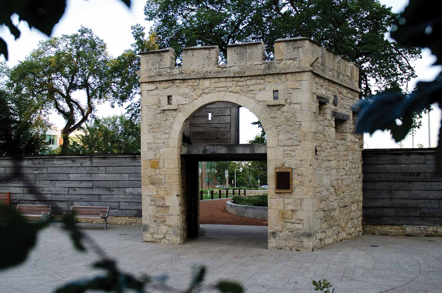 The north entrance to Upper Fort Garry, showing the original stone Governor's Gate flanked by a newer wooden fence.