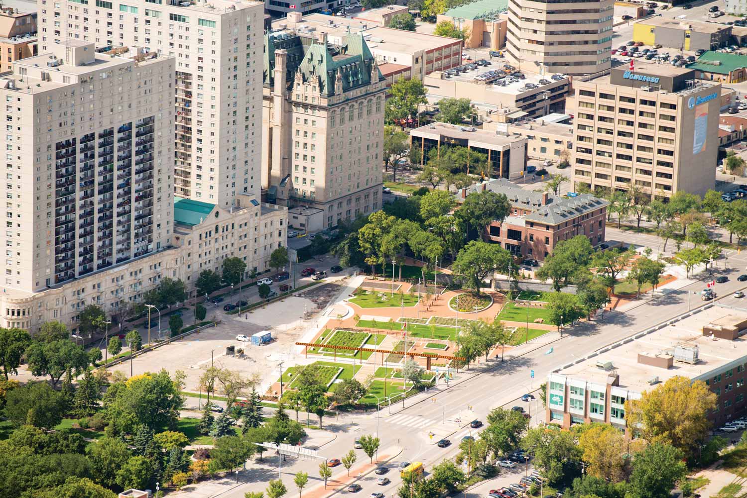Aerial view of Upper Fort Garry Provincial Park in the summer. It is wedge shaped, with paths and gardens. Main street is to its right.