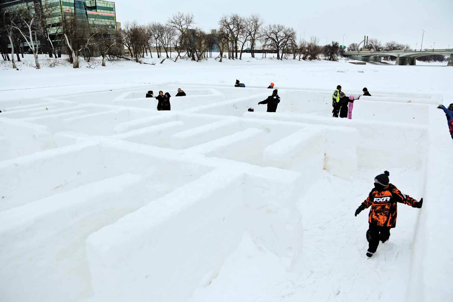 Several adults and children are navigating through a low maze of ice on the skating trail