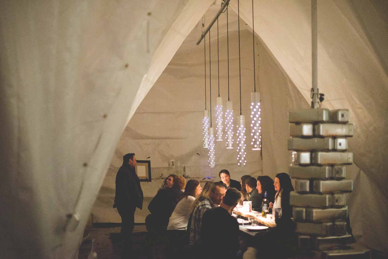 A group of people sitting at a table in a white tent with cozy lighting