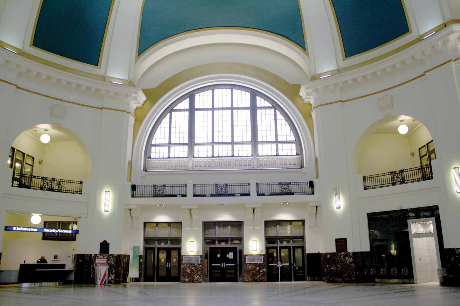 A modern photo of the rotunda in 2015. A large semicircular window and arches are in the center above doorways. An information desk can be seen on the left.