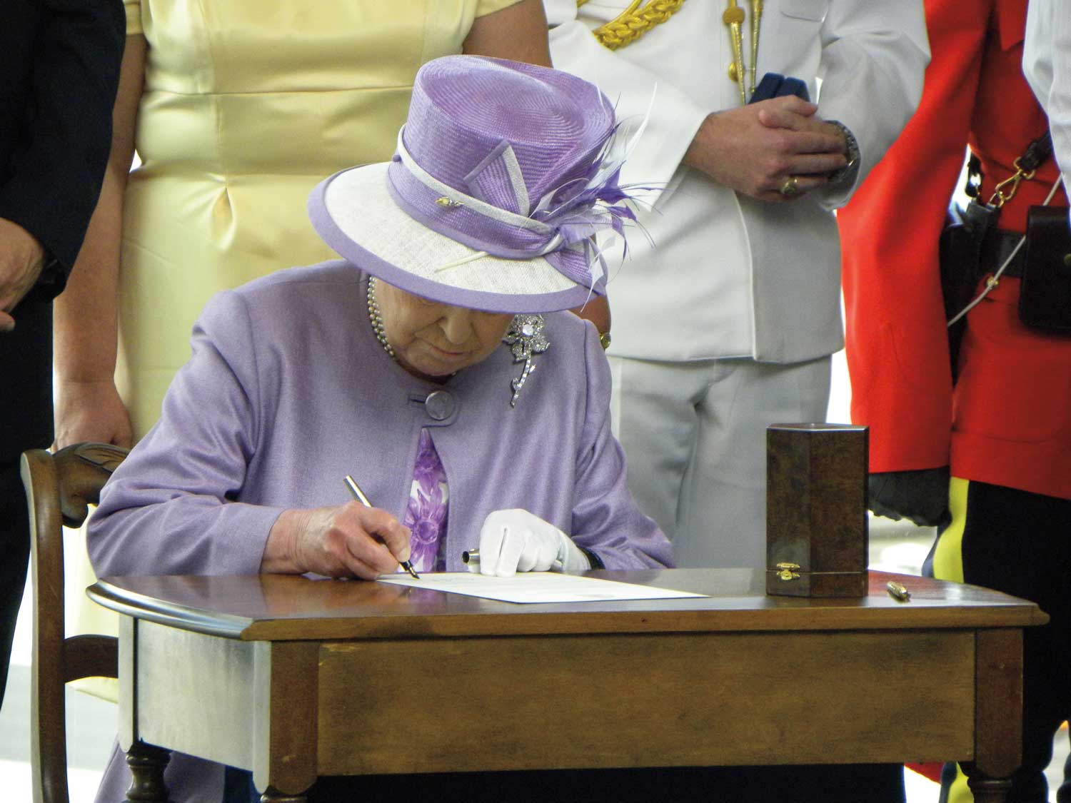 Queen Elizabeth II writing a letter at the James Armstrong Richardson International Airport.