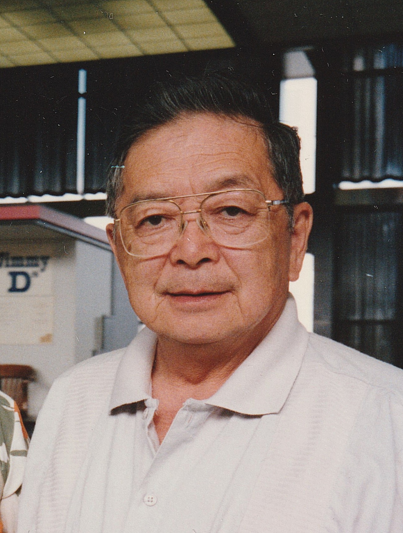 Image shows a man with glasses and a light collared shirt.
