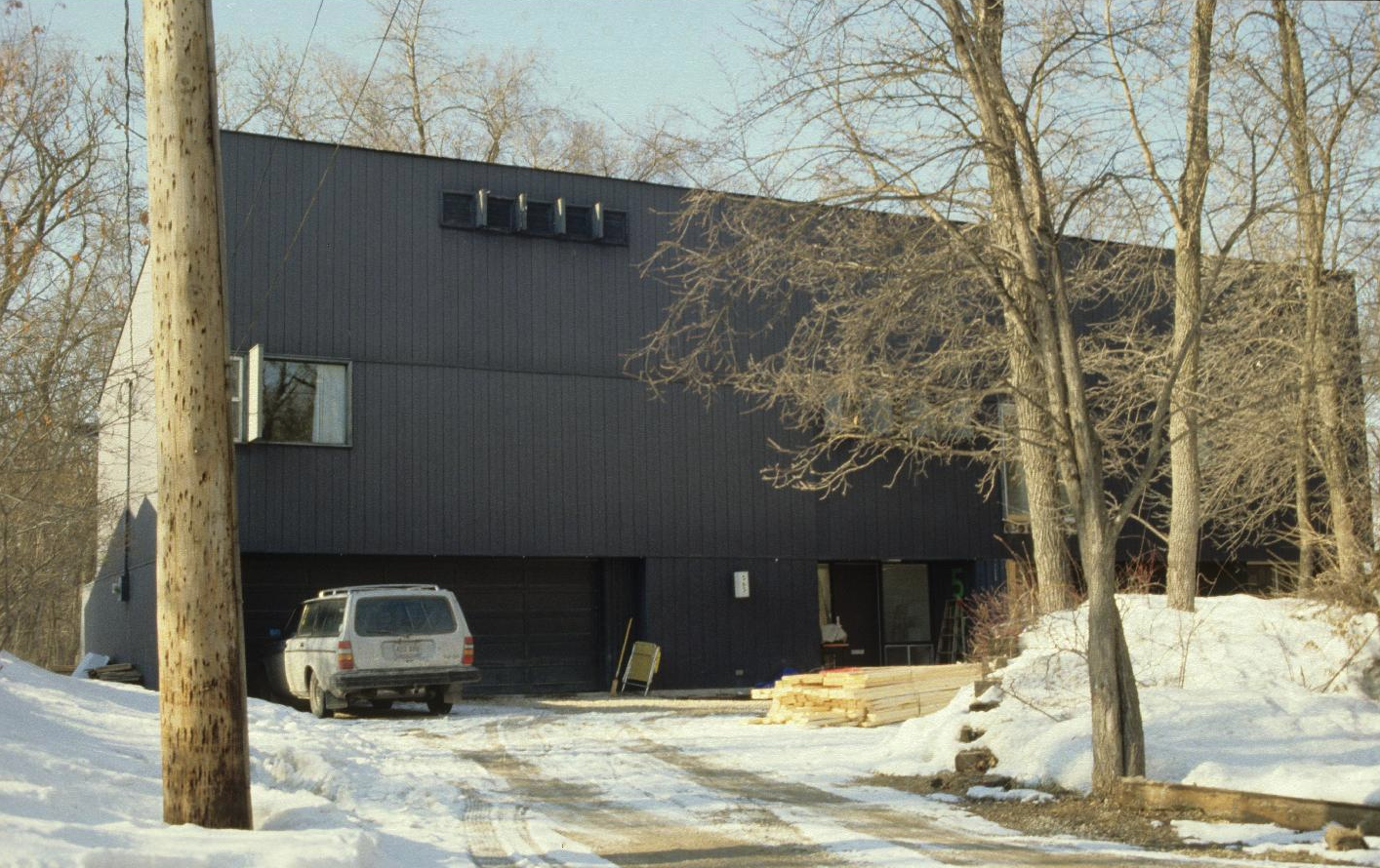 Image shows large residential structure with dark vertical panelling.