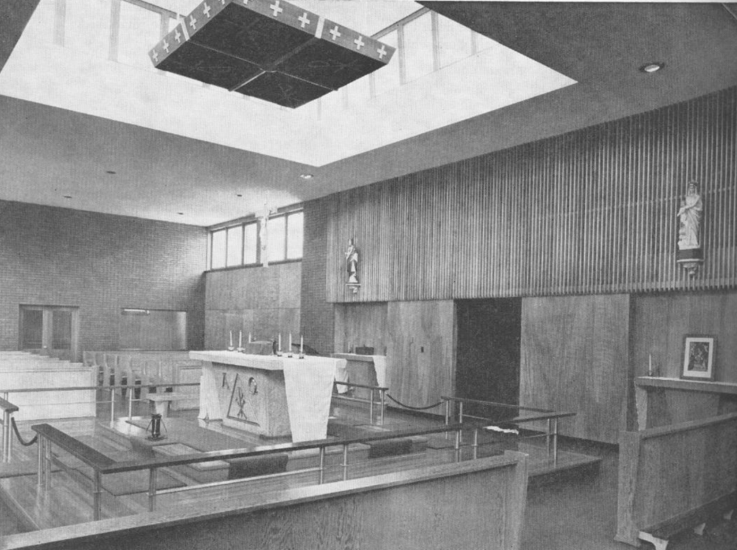 Image shows an archival photograph of the interior for Our Lady of Victory Church. The walls are brick and wood panelled, with a skylight positioned over the altar.