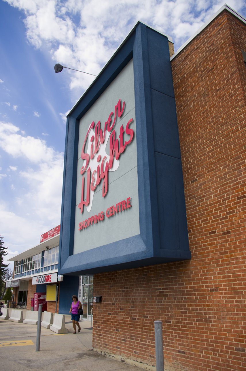 Image shows the signage of Silver Heights Shopping Centre. The signage is prominently featured. It is in shades of blue. The typeface is in red and the star is in the background.