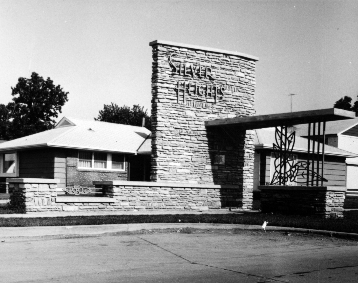 Image shows a black and white image of the Silver Heights Gates, with the signage clearly featured.