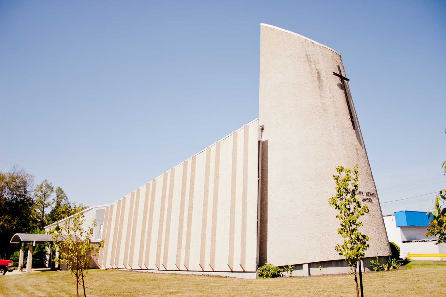 Image shows the exterior for Silver Heights United Church. The building is finished in concrete, with inset concrete on the side.