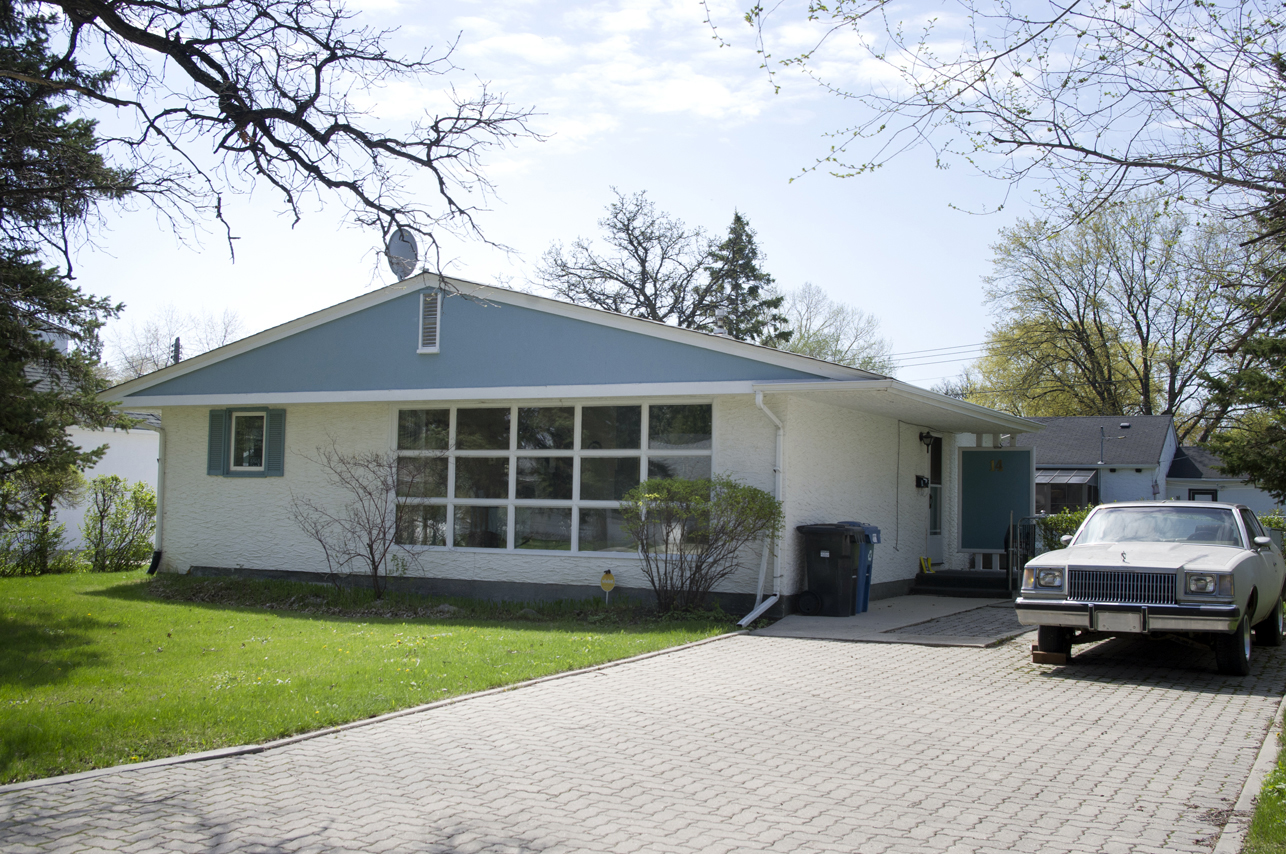 Image shows exterior of home. The roof is blue, and windows are prominently on the side.