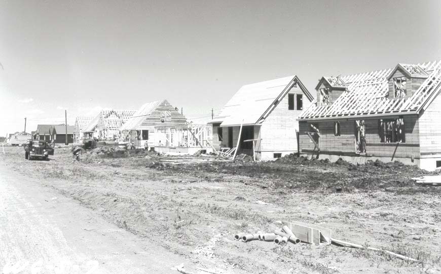 Image shows greyscale image of a street in construction. The homes are in varying stages of construction.