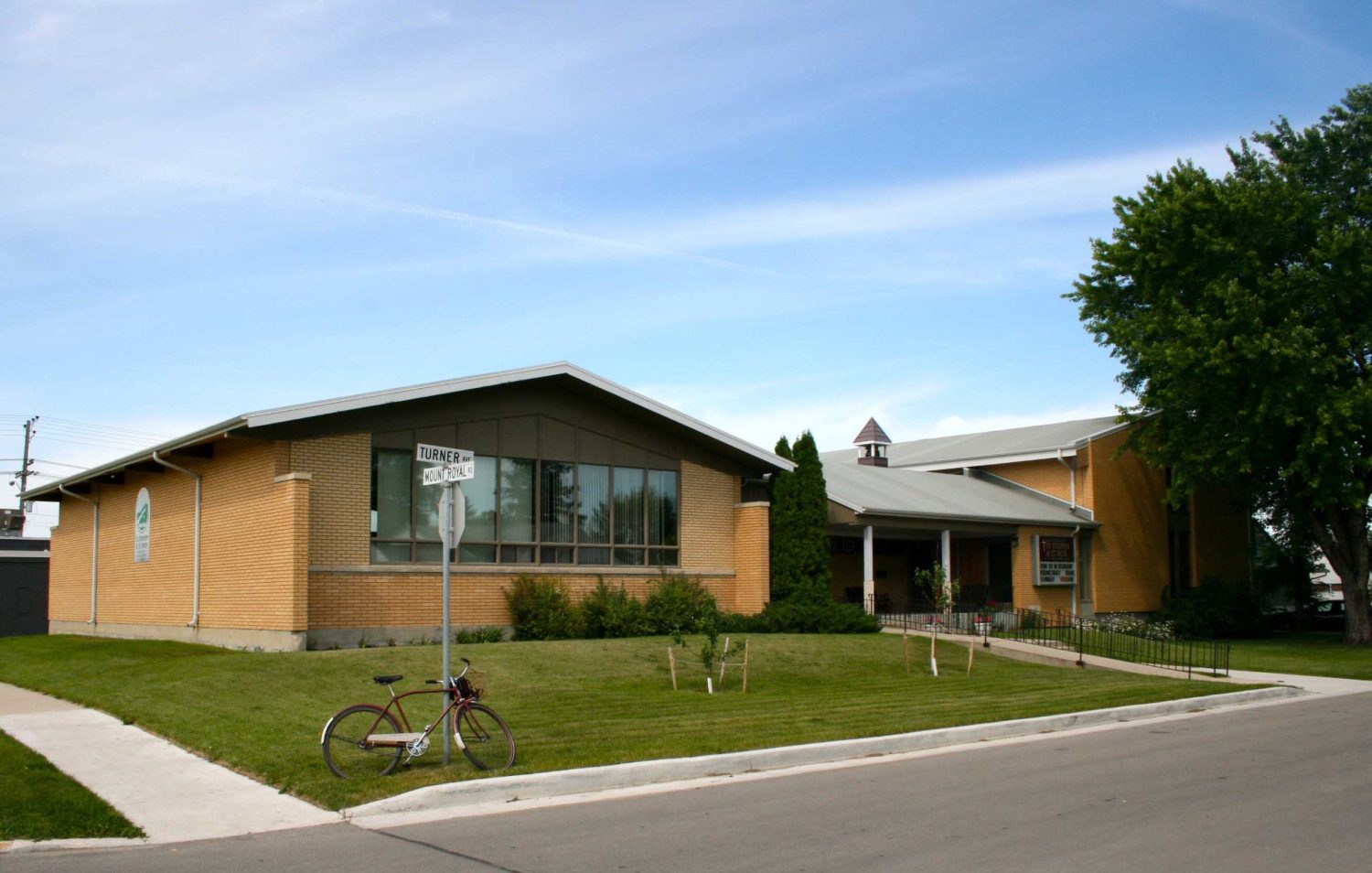 Image shows a large and simple brick church, with large windows fixed on the centre of the building.