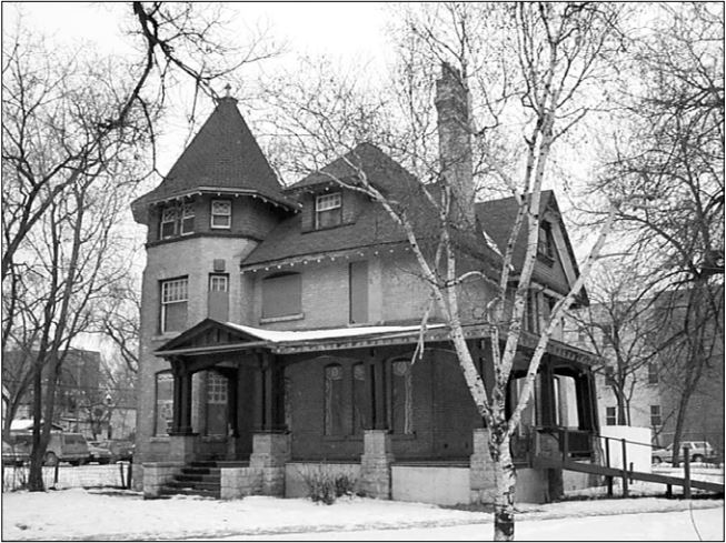 A black-and-white- photograph of the Wilson House. There is a tower on the left side of the building, and a large porch in front.