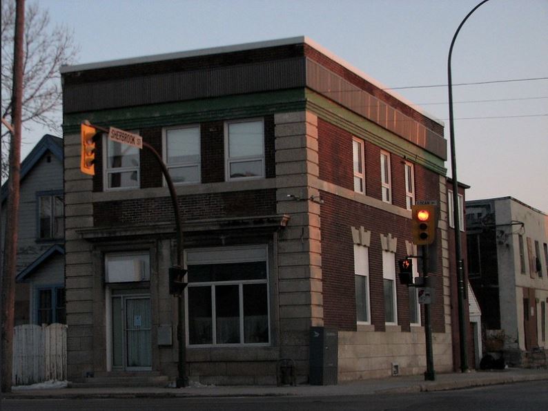 A picture of 646 Logan at sunset. The building is two storeys tall, made of brown brick.