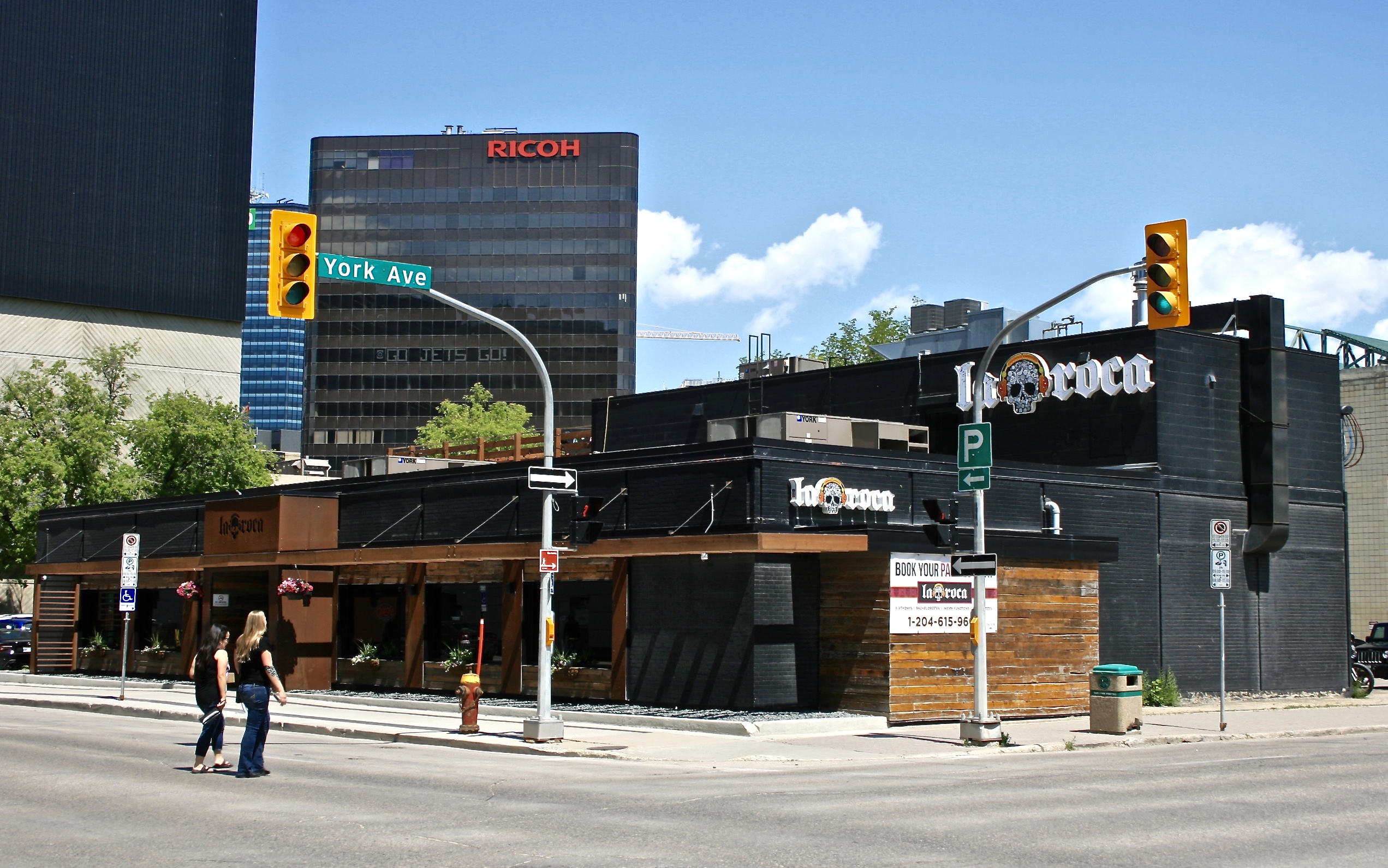 The exterior of the renovated 155 Smith Street. The building is black with wood accents. There is a sign for La Roca with a skull.