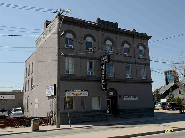 The exterior of The Mount Royal Hotel. The building is grey and there is a sign that says "MOUNT ROYAL HOTEL" above the door.